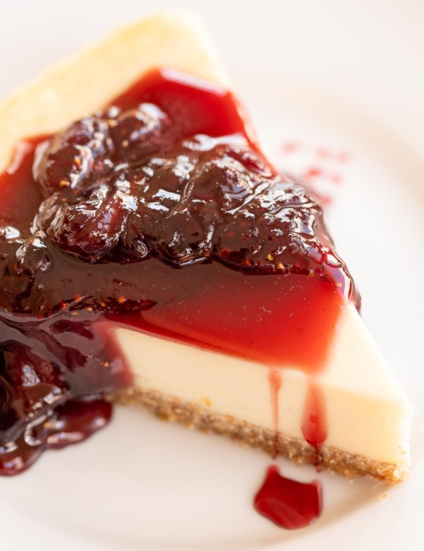 草莓在白板上的一块芝士蛋糕上撒上芝士蛋糕