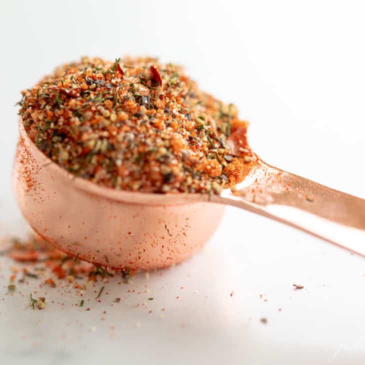 白色背景,充满牛排调味料混合物的铜量杯。