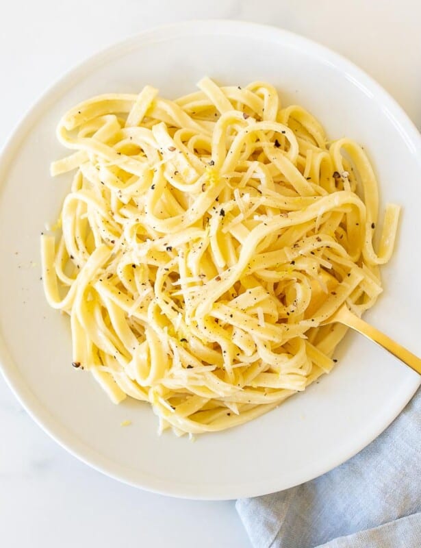 一个白板,装满了碗中装满柠檬胡椒意大利面,将金叉伸到侧面。